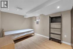 Recessed lighting illuminates this room featuring light wood-finish flooring, neutral wall tones, and an exposed ceiling beam - 