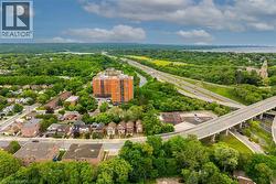 Aerial perspective showcasing a multi-lane highway system, surrounding green spaces, and a residential area with a prominent high-rise building - 
