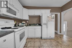 Kitchen featuring white cabinetry, dark speckled countertops, and integrated appliances - 
