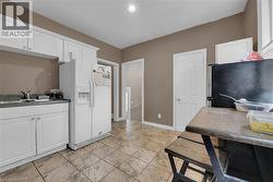 Kitchen featuring white cabinetry, a stainless steel sink, tiled flooring, and neutral wall paint - 