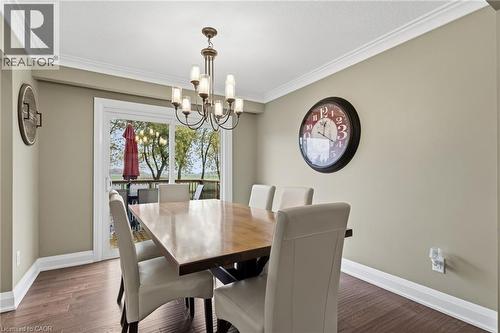 Dining area featuring wood-finish flooring, crown molding, a multi-arm chandelier, and sliding glass doors leading to an outdoor deck - 2116 Binbrook Road E, Hamilton, ON - Indoor Photo Showing Dining Room