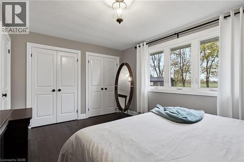 Bedroom featuring dark wood-finish flooring, light gray walls, and multiple panel doors with dark hardware - 2116 Binbrook Road E, Hamilton, ON - Indoor Photo Showing Bedroom