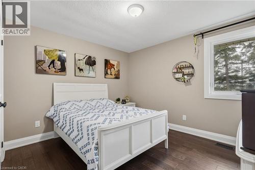 Expansive room featuring dark wood-finish flooring, light tan wall paint, white trim, and a white framed window - 2116 Binbrook Road E, Hamilton, ON - Indoor Photo Showing Bedroom