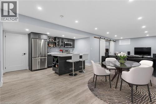 Open-concept recreational space featuring a fully equipped wet bar with stainless steel appliances, a center island with seating, recessed lighting, and wood-finish flooring - 2116 Binbrook Road E, Hamilton, ON - Indoor Photo Showing Dining Room