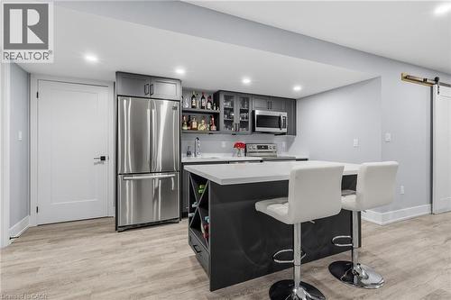 Contemporary kitchenette featuring a large stainless steel refrigerator, built-in microwave, and ample gray cabinetry with glass-front accents - 2116 Binbrook Road E, Hamilton, ON - Indoor Photo Showing Kitchen
