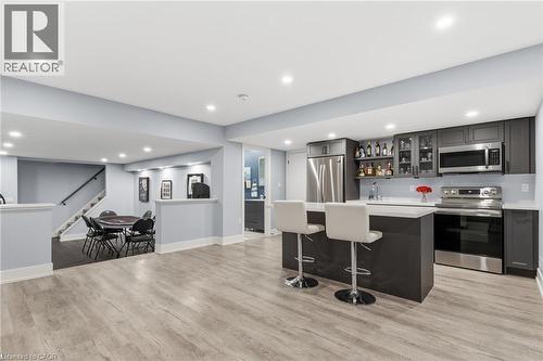 Open-concept basement featuring wood-finish flooring, recessed lighting, and a contemporary wet bar with stainless steel appliances - 2116 Binbrook Road E, Hamilton, ON - Indoor Photo Showing Kitchen