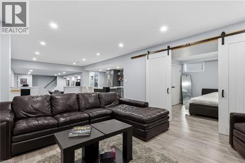 Finished lower level featuring recessed lighting, wood-finish flooring, white barn doors with black hardware, a built-in wet bar, and an open-concept layout - 2116 Binbrook Road E, Hamilton, ON - Indoor Photo Showing Living Room