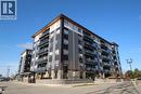 Contemporary multi-story building featuring black, white, and grey siding, private balconies with glass railings, and a wood-finish soffit - 247 Northfield Drive E Unit# 207, Waterloo, ON  - Outdoor With Balcony With Facade 