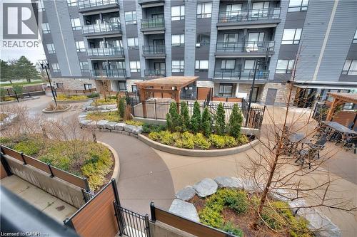 Expansive courtyard featuring a winding concrete pathway, multiple pergolas, and decorative landscaping with various plantings and stone elements - 247 Northfield Drive E Unit# 207, Waterloo, ON - Outdoor With Balcony