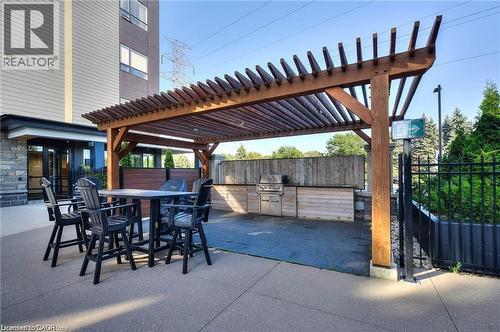 Outdoor entertainment area featuring a substantial wood pergola, integrated barbecue station, and concrete patio flooring - 247 Northfield Drive E Unit# 207, Waterloo, ON - Outdoor With Exterior