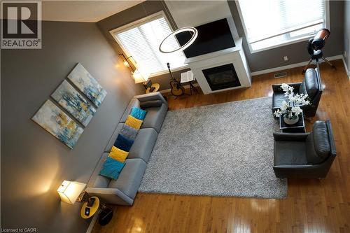 Spacious living area featuring polished wood-finish flooring, a contemporary fireplace with a white mantel, and a large area rug - 704 Zurich Drive, Waterloo, ON - Indoor With Fireplace