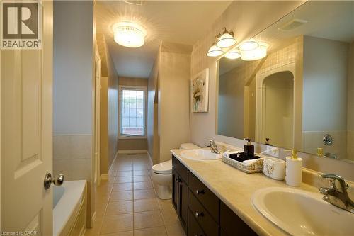 Bathroom featuring a dual-sink vanity with dark wood-finish cabinetry, a large wall-mounted mirror, and tile flooring - 704 Zurich Drive, Waterloo, ON - Indoor Photo Showing Bathroom