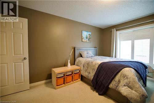 Bedroom featuring a four-panel interior door, plush carpeting, and warm-toned wall paint - 704 Zurich Drive, Waterloo, ON - Indoor Photo Showing Bedroom