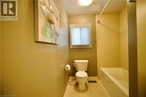 Bathroom featuring a white bathtub, ceramic tile surround, white toilet, and tile flooring - 704 Zurich Drive, Waterloo, ON - Indoor Photo Showing Bathroom
