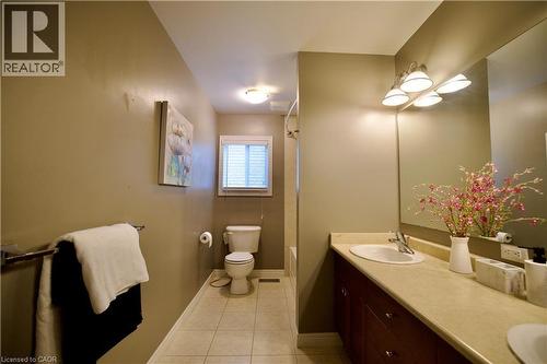 Bathroom featuring a long single-sink vanity with wood-finish cabinetry, a large wall-mounted mirror, and a multi-bulb light fixture - 704 Zurich Drive, Waterloo, ON - Indoor Photo Showing Bathroom