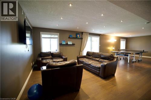 Spacious recreation room featuring recessed lighting, dark wood-finish flooring, and multiple windows with white blinds - 704 Zurich Drive, Waterloo, ON - Indoor