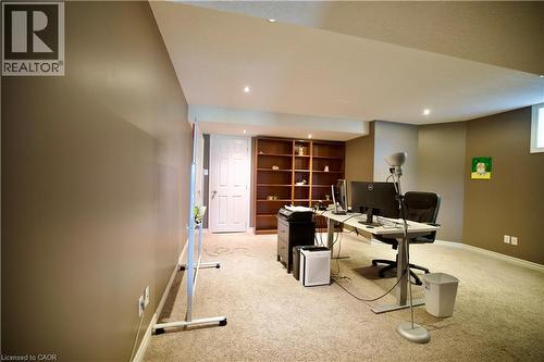 Spacious lower level featuring recessed lighting, light-colored carpeting, a built-in wood-finish shelving unit, and a white paneled door - 704 Zurich Drive, Waterloo, ON - Indoor
