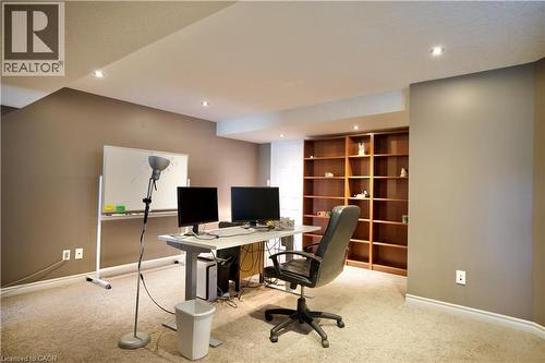 Recessed lighting illuminates a versatile space featuring a built-in wood-finish bookshelf, neutral-toned walls, and plush carpeting - 704 Zurich Drive, Waterloo, ON - Indoor Photo Showing Office