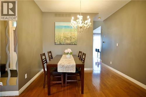 Warm-toned wood-finish flooring complements the neutral wall color in this dining area - 704 Zurich Drive, Waterloo, ON - Indoor Photo Showing Dining Room