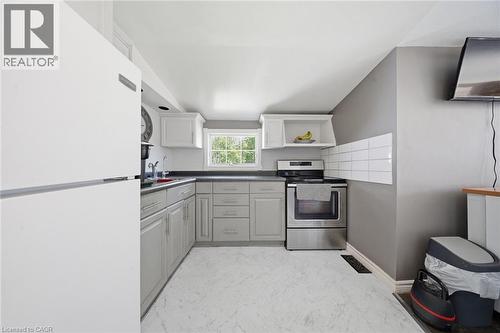Kitchen featuring light gray cabinetry, dark countertops, a stainless steel range, white subway tile backsplash, and a window providing natural light - 401 West Street, Simcoe, ON - Indoor Photo Showing Kitchen
