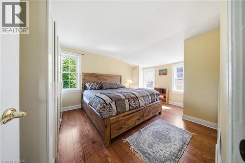 Bedroom featuring rich wood-finish flooring, multiple windows, a sloped ceiling, and white trim - 401 West Street, Simcoe, ON - Indoor Photo Showing Bedroom