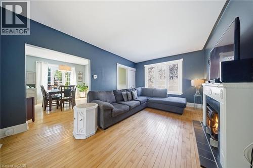 Spacious living area featuring light wood-finish flooring, a white mantel, and a dark tile hearth - 401 West Street, Simcoe, ON - Indoor Photo Showing Living Room With Fireplace
