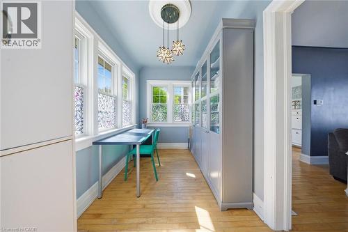 Dedicated workspace featuring expansive windows, built-in cabinetry with glass panels, wood-finish flooring, a decorative ceiling medallion, and contemporary pendant lighting - 401 West Street, Simcoe, ON - Indoor Photo Showing Other Room
