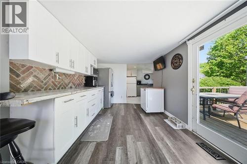 Contemporary kitchen featuring white cabinetry, herringbone brick-patterned backsplash, and wood-finish flooring - 401 West Street, Simcoe, ON - Indoor Photo Showing Kitchen
