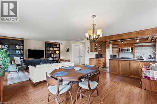 Open-concept living space featuring wood-finish flooring, a dining area with a chandelier, and a kitchen with custom wood cabinetry and stone backsplash - 3 San Pedro Drive, Hamilton, ON - Indoor