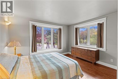 Bright interior room featuring a large window with white trim, wood-finish flooring, and light gray wall paint - 3 San Pedro Drive, Hamilton, ON - Indoor Photo Showing Bedroom