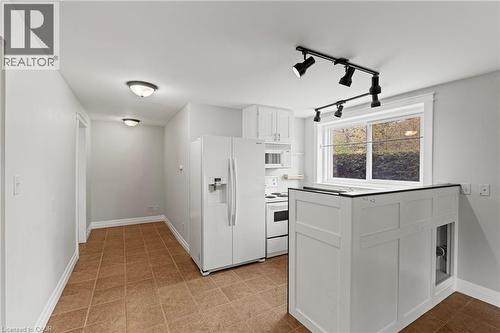 Kitchen featuring white cabinetry, white appliances, track lighting, and a window with exterior shrubbery - 3 San Pedro Drive, Hamilton, ON - Indoor Photo Showing Other Room