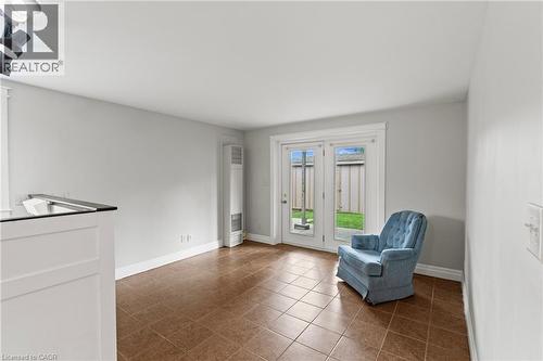 Spacious room featuring neutral walls, brown tile flooring, white baseboards, and white French doors opening to an outdoor area - 3 San Pedro Drive, Hamilton, ON - Indoor
