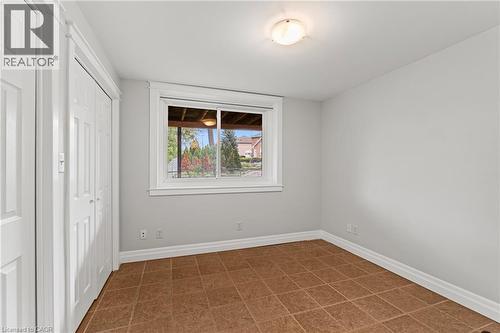Room featuring neutral wall paint, tiled flooring, a window with white trim, a flush-mount ceiling light, and a bi-fold closet - 3 San Pedro Drive, Hamilton, ON - Indoor Photo Showing Other Room