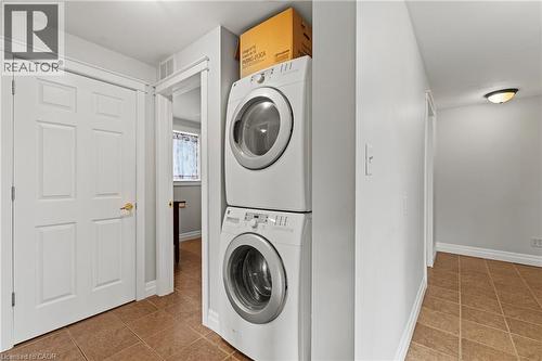 Dedicated laundry area featuring a stacked washer and dryer unit, neutral wall paint, and tile flooring - 3 San Pedro Drive, Hamilton, ON - Indoor Photo Showing Laundry Room