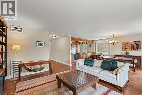 Open-concept living area featuring wood-finish flooring, built-in shelving, a kitchen pass-through, and a dining area with an overhead chandelier - 3 San Pedro Drive, Hamilton, ON - Indoor Photo Showing Living Room