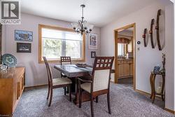 Dining area featuring a central chandelier, wood-trimmed window, and neutral wall color - 