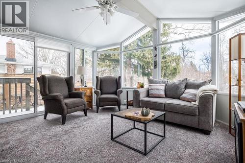 Sunroom featuring an angular wall of windows, a vaulted ceiling with a ceiling fan, plush gray carpeting, and a sliding glass door providing exterior access - 19 Chateau Court, Hamilton, ON - Indoor Photo Showing Living Room