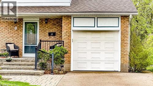 Brick facade residence featuring a single-car garage, stone paver steps, a storm door entry, and black metal handrailing - 19 Chateau Court, Hamilton, ON - Outdoor With Deck Patio Veranda With Exterior