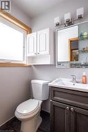 Bathroom with a window featuring wood trim, a white vanity with an integrated sink, a wall-mounted mirror, and overhead lighting - 