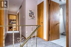 Hallway featuring carpeted flooring and a brass railing - 