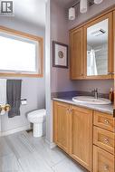 Bathroom with a light wood-finish vanity, integrated sink, and granite-look countertop - 