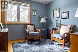 Room featuring wood-finish flooring, light blue walls, and a large window with natural wood trim - 