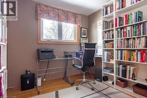 Dedicated office space featuring built-in white shelving, wood-finish flooring, a window with wood trim, and neutral wall tones - 19 Chateau Court, Hamilton, ON - Indoor Photo Showing Office