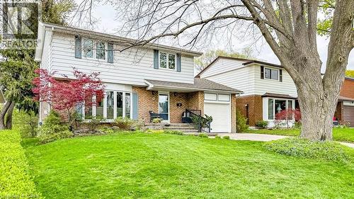 Two-story residence featuring a white horizontal siding exterior with contrasting blue window shutters and brick accents - 19 Chateau Court, Hamilton, ON - Outdoor