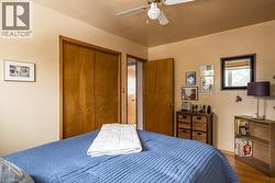 Bedroom featuring wood-finish flooring, a ceiling fan, and a built-in closet with double doors - 
