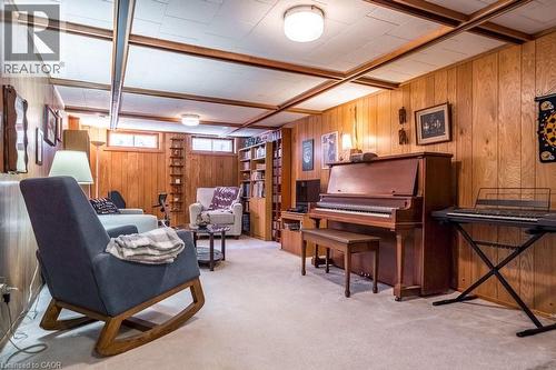 Finished room featuring wood-panel walls, light-colored carpeting, a drop ceiling with exposed wood beams, and built-in shelving - 19 Chateau Court, Hamilton, ON - Indoor Photo Showing Other Room