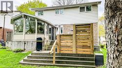 Rear exterior featuring a multi-level wood deck, a sunroom extension with extensive windows, and natural wood privacy screening - 
