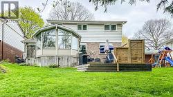 Expansive green lawn with a multi-level deck and an octagonal sunroom extension - 