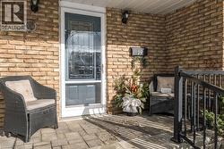 Inviting brick exterior porch with paver flooring, featuring a storm door with decorative grille, and a black metal handrail - 