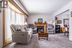 Living area featuring a bay window with wood trim, wood-surround fireplace, and light-colored carpet flooring - 